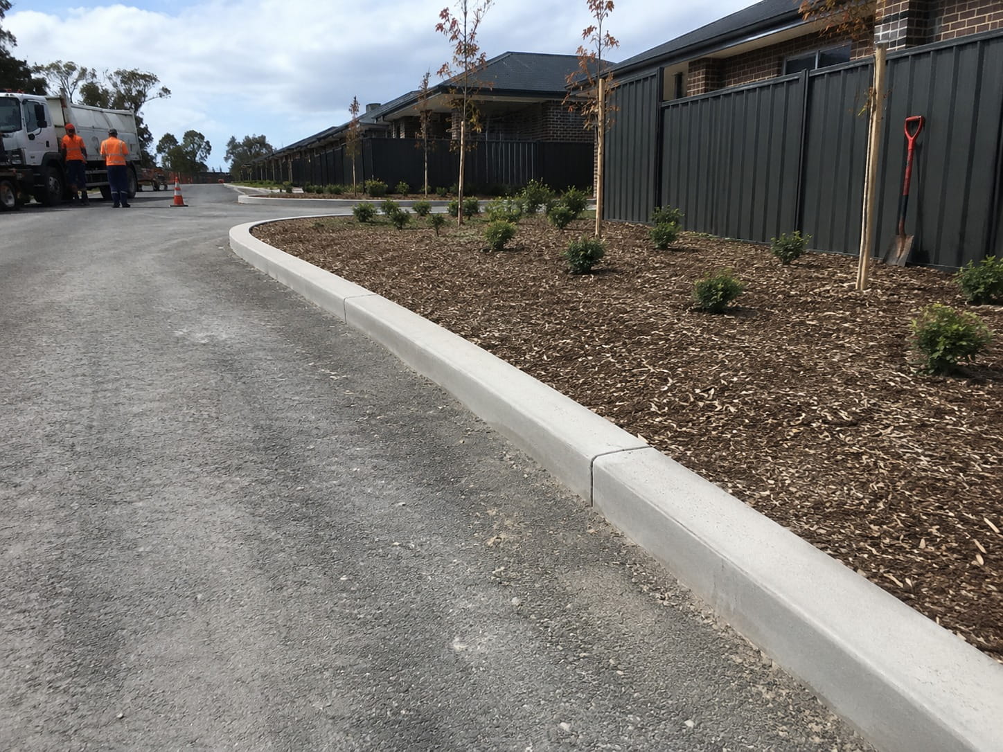 Curved concrete kerb edging a mulched garden bed along a Perth street